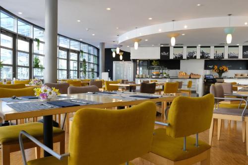 a restaurant with tables and yellow chairs at FOUR Munich Neue Messe in Munich