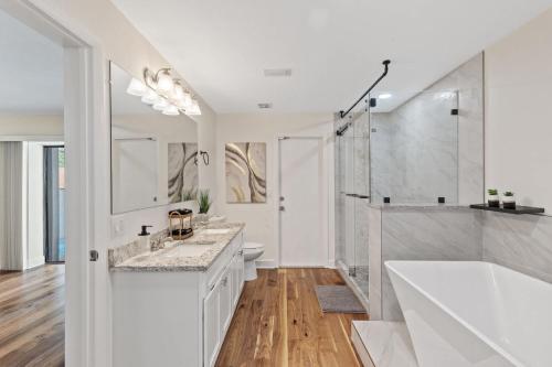a white bathroom with a tub and a shower at Sunshine State Retreat Luxury Pool Home in Brandon