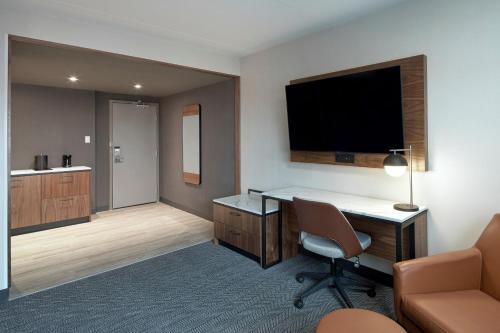 a hotel room with a desk and a flat screen tv at Courtyard by Marriott Regina Downtown in Regina
