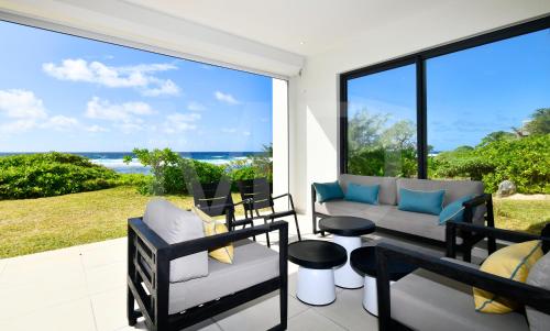 a patio with a couch and chairs and a view of the ocean at White&Blue Beachfront Luxury Poste Lafayette in Poste Lafayette
