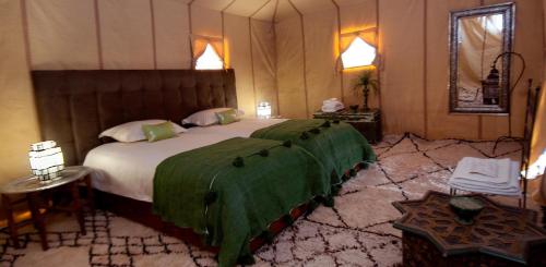 a bedroom with a large bed with a green blanket at Royal Sands Camp in Merzouga