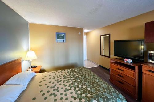 a hotel room with a bed and a flat screen tv at Econo Lodge Motel Village in Calgary
