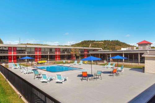 a swimming pool with chairs and blue umbrellas at Econo Lodge Cave City in Cave City