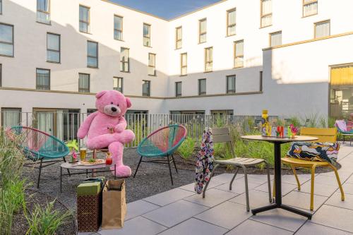 a large pink teddy bear sitting on a chair at Moxy Outletcity Metzingen in Metzingen
