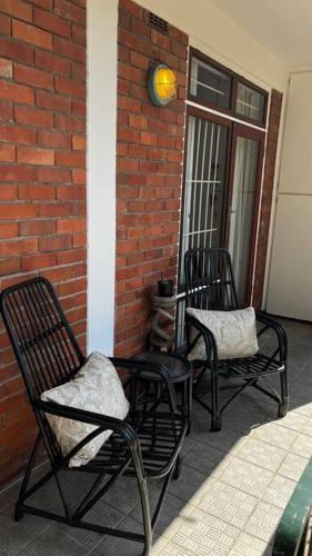two chairs sitting on a porch with a brick wall at Retro City Center Gem by ARPA Hospitalities in Stellenbosch