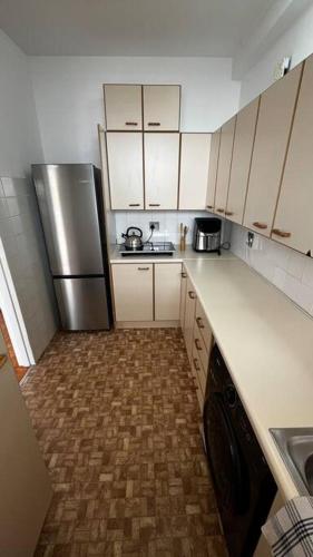 a kitchen with white cabinets and a stainless steel refrigerator at Retro City Center Gem by ARPA Hospitalities in Stellenbosch
