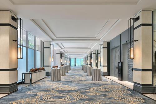 a hallway with a row of tables and a row of windows at The Westin Mumbai Powai Lake in Mumbai