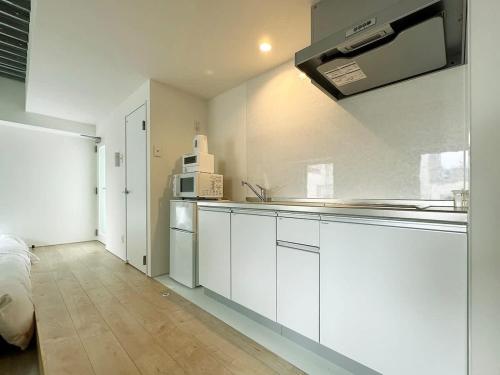 a kitchen with white cabinets and a microwave at bHOTEL Arts Dobashi - Modern 1 BR apartment good for 6 people in Hiroshima