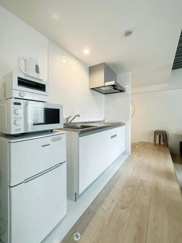 a kitchen with white appliances and a wooden floor at bHOTEL Arts Dobashi - Modern 1 BR apartment good for 6 people in Hiroshima