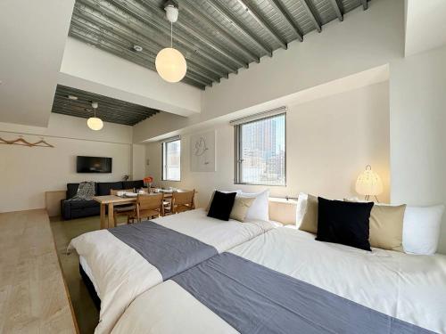 a bedroom with a large bed and a living room at bHOTEL Arts Dobashi - Modern 1 BR apartment good for 6 people in Hiroshima