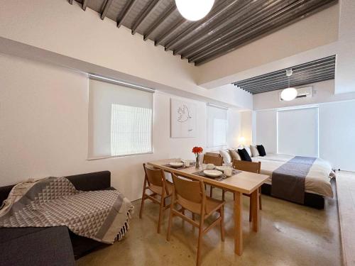 a room with a bed and a table and a couch at bHOTEL Arts Dobashi - Modern 1 BR apartment good for 6 people in Hiroshima