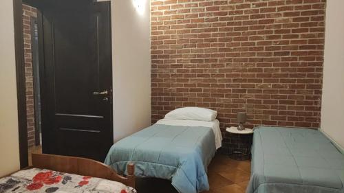 a room with two twin beds and a brick wall at B&B EMPIRA Lamezia Terme in Lamezia Terme