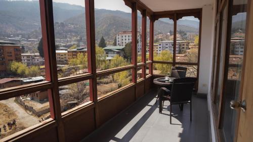 a balcony with a table and chairs looking out at the city at Hotel Osel in Thimphu