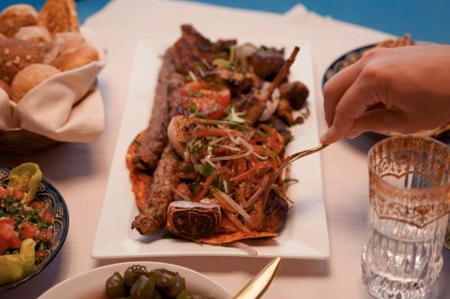 a table with a plate of food and a person holding a fork at Al Wathba, a Luxury Collection Desert Resort & Spa, Abu Dhabi in Abu Dhabi