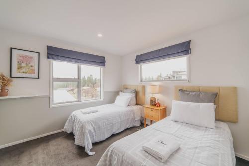 two beds in a room with two windows at Hillside Haven Perfect Getaway in Lake Tekapo in Lake Tekapo