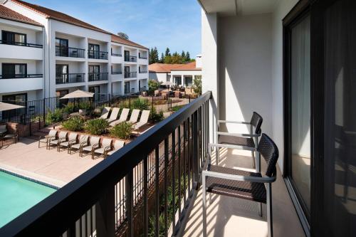 a balcony of a hotel with a pool and chairs at Courtyard San Jose Cupertino in Cupertino