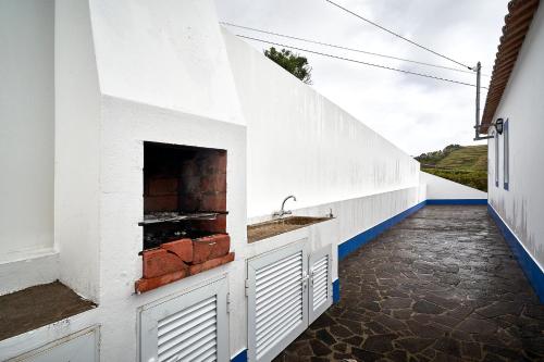 a white kitchen with a sink and a fireplace at Casa Azul da Corisca in São Lourenço