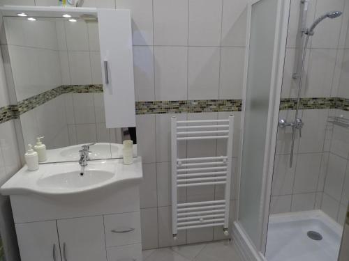 a white bathroom with a sink and a shower at Alabárdos Panzió és Apartmanház in Esztergom
