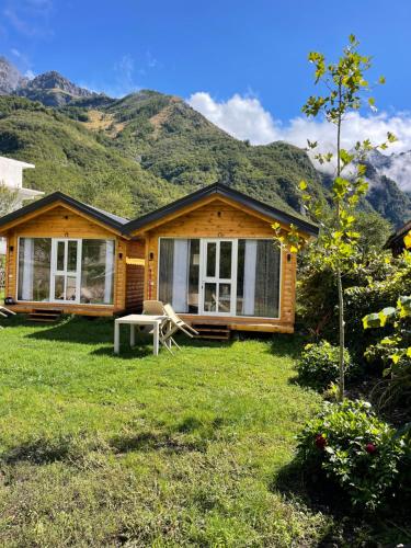 a log cabin with a table and a chair in the yard at Thethi Mountain Villas in Theth