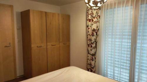a bedroom with a bed and a cabinet and a window at Studio au pied de la télécabine, SaastalCards Saas-Fee in Saas-Fee