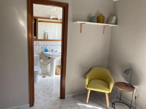 a bathroom with a yellow chair and a sink at Pool House Mencey in El Médano