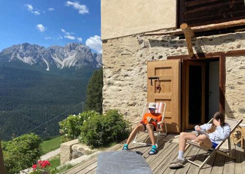 a man sitting in a chair on the porch of a house at Tabià di Francesca - fienile tra le montagne silenziose in Candide