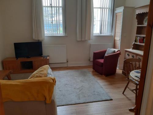 a living room with a couch and a tv at Ground Floor Barmouth Centre Apartment With Garden in Barmouth
