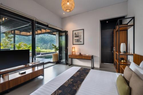 a bedroom with a large bed and a television at Zenubud in Ubud