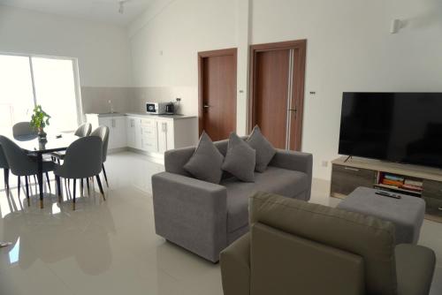 a living room with a couch and a tv and a table at TME Retreats Dhigurah in Dhigurah