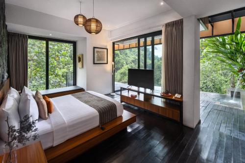 a bedroom with a bed and a tv and windows at Zenubud in Ubud