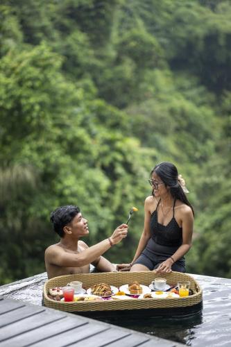 a man and a woman sitting in the water eating food at Zenubud in Ubud