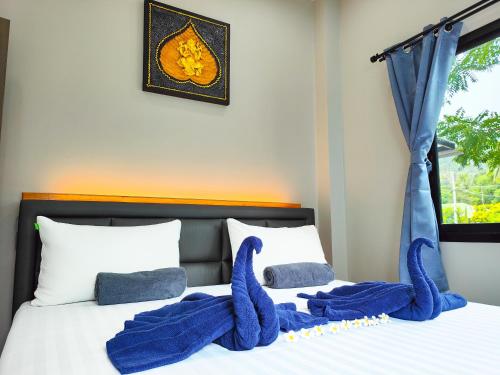 two blue stuffed animals sitting on top of a bed at The Blue House Lipa Noi in Koh Samui 