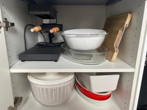 une étagère avec des bols et d'autres ustensiles de cuisine dans l'établissement Maison cosy en plein coeur de Ouistreham, à Ouistreham