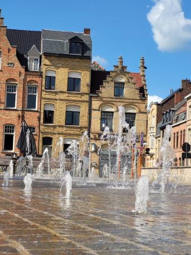 a fountain in the middle of a city with buildings at Holiday Home Alice House in Ieper