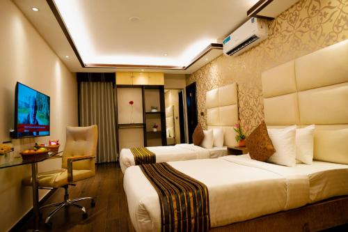 a hotel room with two beds and a desk at Royal Residence Dhaka in Dhaka