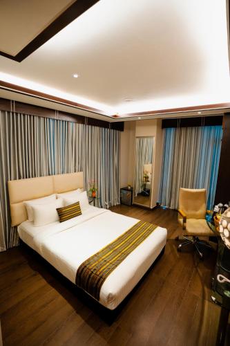 a large bedroom with a large bed and a chair at Royal Residence Dhaka in Dhaka