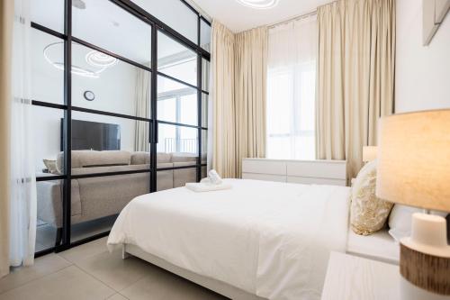 a bedroom with a white bed and a large window at Socio Tower1 - Dubai Hills Modern Urban Retreat in the City by Serenity Living Holiday Homes in Dubai