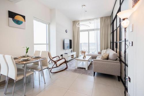 a living room with a table and chairs and a couch at Socio Tower1 - Dubai Hills Modern Urban Retreat in the City by Serenity Living Holiday Homes in Dubai