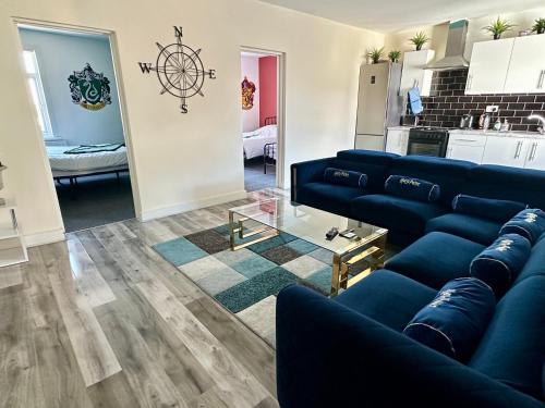 a living room with blue couches and a kitchen at HP Wizards Corner Spacious 4 bed near Watford Junction in Watford