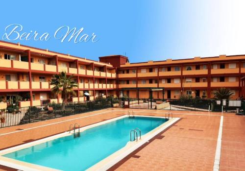 un hôtel avec une piscine devant un bâtiment dans l'établissement BeiraMar La Caleta, piscina y wifi gratis, tranquilidad junto al atlántico, à Parque Holandes