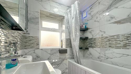 a white bathroom with a tub and a sink at 4 Bedroom Excellent Home Large Spacious New Built Detached House Driveway Free Parking in Stockport