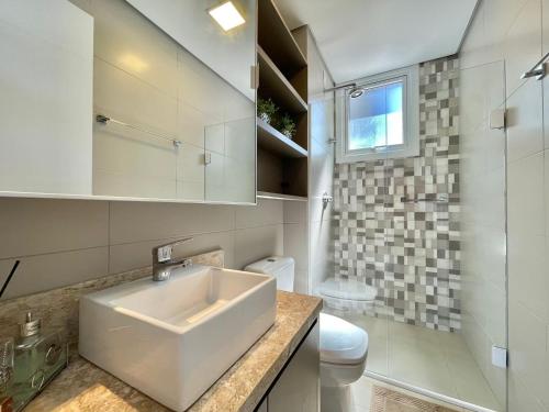 a white bathroom with a sink and a toilet at Apartamento de Última Geração em Atlântida in Xangri-lá