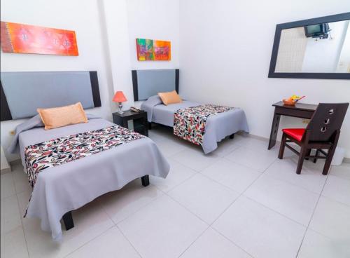 a room with two beds and a table and a chair at Principe Hoteles SECHURA in Sechura