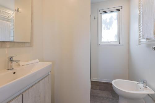 a white bathroom with a sink and a window at Camping Bungalow Lido in Capoliveri