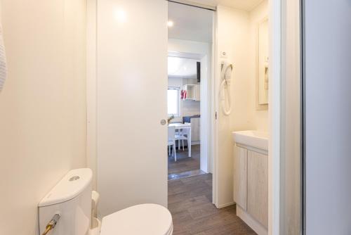 a white bathroom with a toilet and a sink at Camping Bungalow Lido in Capoliveri