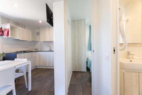 a kitchen with white cabinets and a white table at Camping Bungalow Lido in Capoliveri