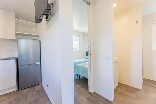 a kitchen with a refrigerator and a room with a table at Camping Bungalow Lido in Capoliveri