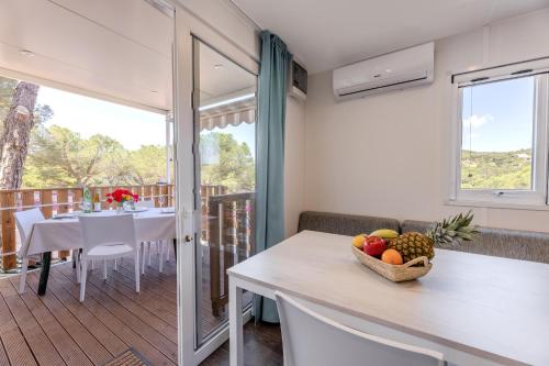 a kitchen and dining room with a table with a bowl of fruit at Camping Bungalow Lido in Capoliveri