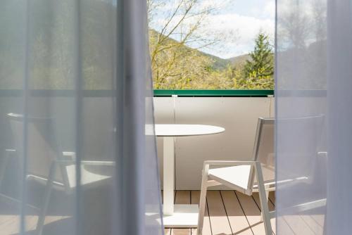a table and chairs in a room with a window at Eau Thermale Avène l'hôtel in Avène