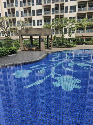 a large blue swimming pool in front of a building at Green Sedayu Apartment Family Suite by Ellison in Jakarta